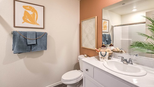 Attached to the Bedroom One Suite, our 1334 model bathroom with granite countertops at the Bath Vanity, a walk-in shower, mirror, and white cabinets.