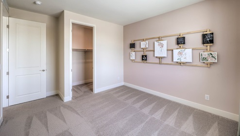 Bedroom Two in our Heartland Summit 4425 model with carpet flooring, a walk-in closet, and a window.