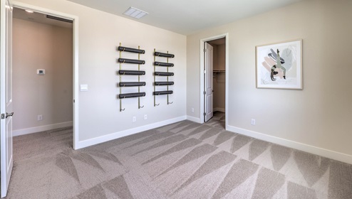 The Office/Bedroom Three option in our Heartland Summit 3765 model with carpet flooring, a walk-in closet, and a window, furnished with a desk and chairs.