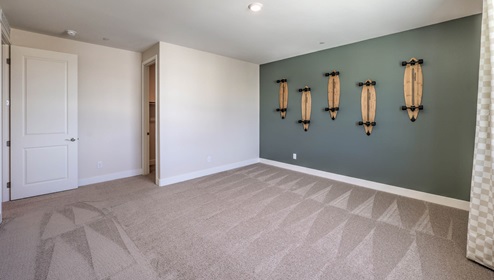 The Bedroom Three option in our Heartland Summit 3765 model with carpet flooring, a walk-in closet, and a window