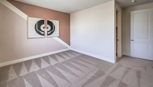 Bedroom Four in our Heartland Summit 4425 model with carpet flooring, a walk-in closet, and a window.