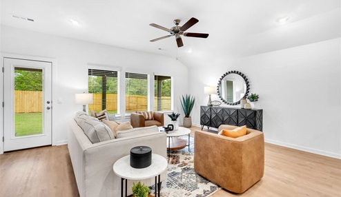 Living room area featuring white walls, light colored floors with three large windows. Back door leading to patio area.