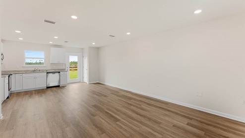 Open living room and kitchen with EVP flooring and granite countertops and stainless-steel appliances.