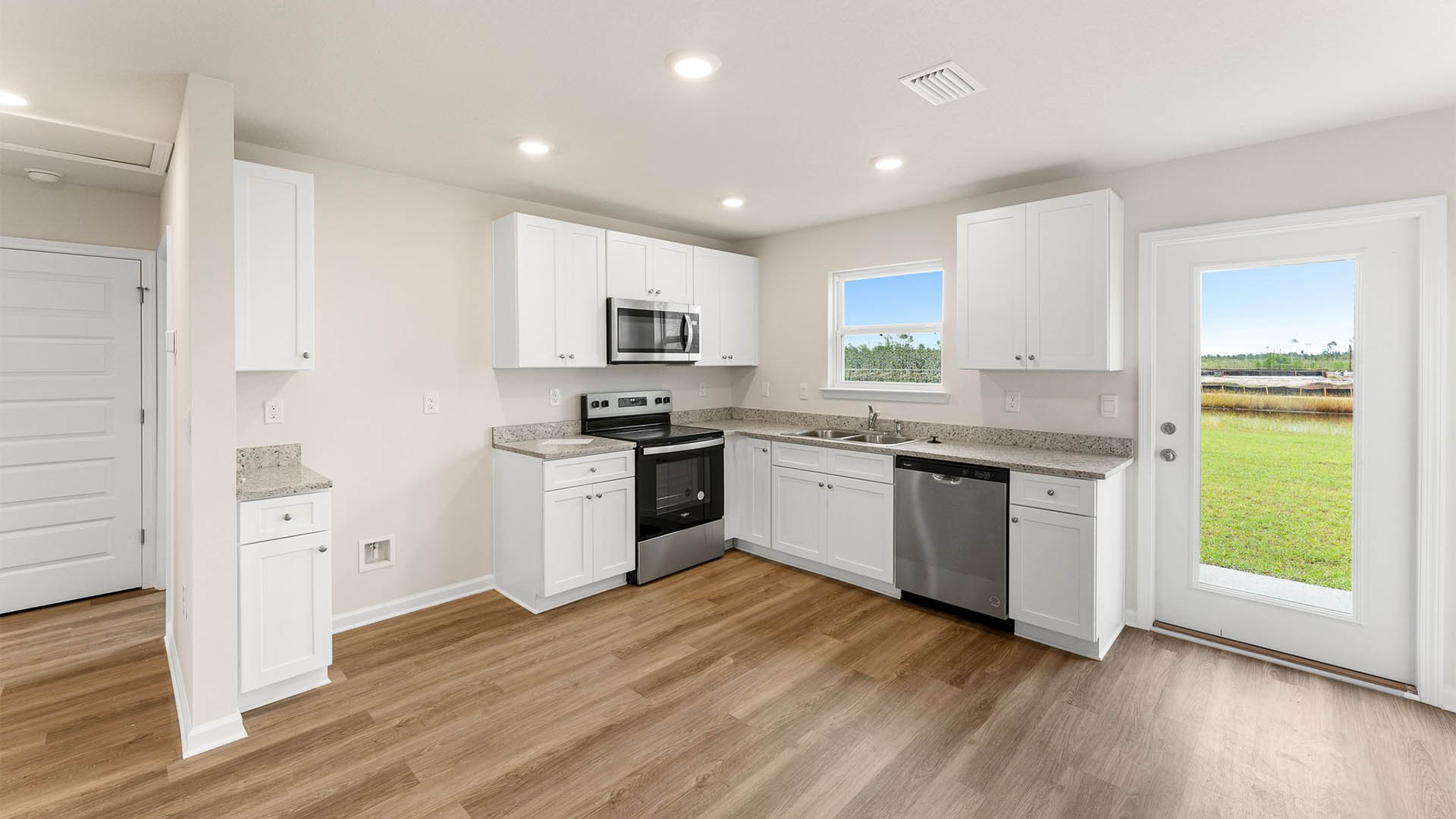 Kitchen with EVP flooring and granite countertops and stainless-steel appliances and hallway and backdoor.