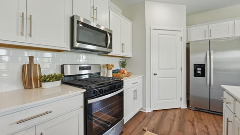 Open concept kitchen with large island, white cabinets and countertops, and stainless steel appliances
