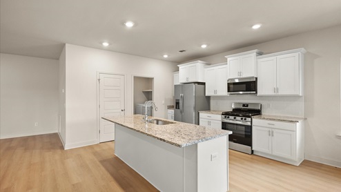 Spacious kitchen with granite countertops, island, and stainless-steel appliances.