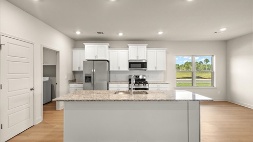 Spacious kitchen with granite countertops, island, and stainless-steel appliances.
