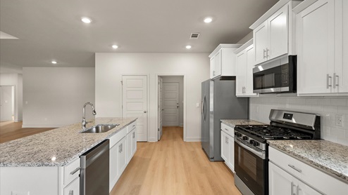 Spacious kitchen with granite countertops, island, and stainless-steel appliances.