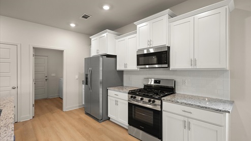 Spacious kitchen with granite countertops, island, and stainless-steel appliances.