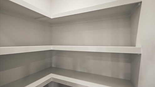 Pantry with wood shelving and recessed lighting.