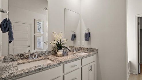 Primary bathroom with double vanity, recessed lighting, double mirrors.