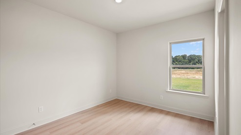 Additional bedroom with hardwood flooring, window, and recessed lighting