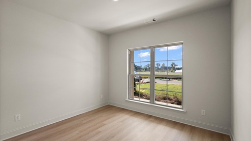 Additional bedroom with hardwood flooring, window, and recessed lighting