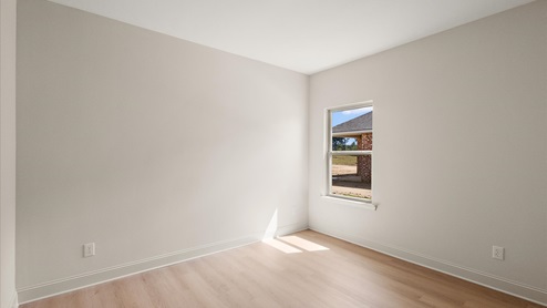 Additional bedroom with hardwood flooring, window, and recessed lighting