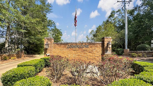 Cornerstone community entrance monument with American Flag and blue sky.