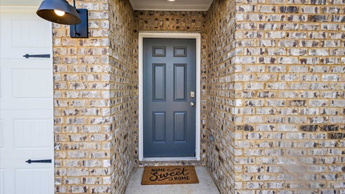 Front porch with multi color brown brick and navy door.