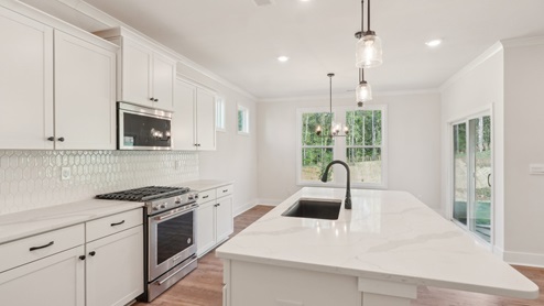 kitchen and island with hanging lights, white cabinets, and stainless steel appliances