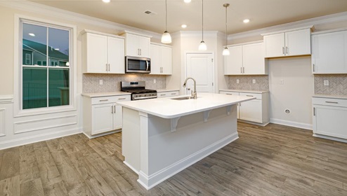Kitchen and island with white cabinets, tile backsplash, quartz countertops, and stainless steel appliances