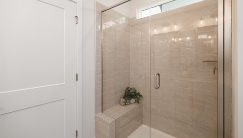 Primary bathroom with double sink vanity, white counters and cabinets, and large standing glass door shower