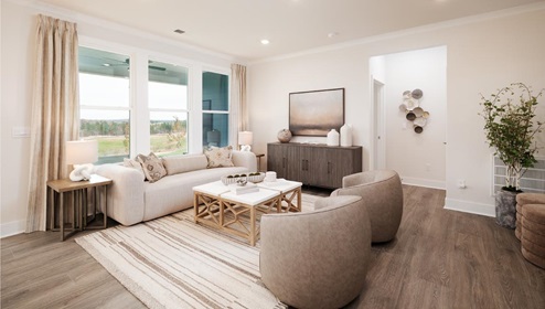 Living room area with large windows beside kitchen