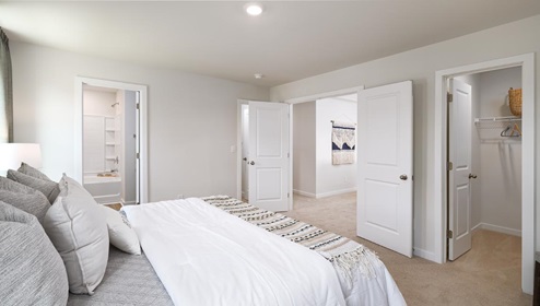 Carpeted primary bedroom with large windows