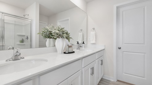 Primary bathroom with double vanity and glass door shower