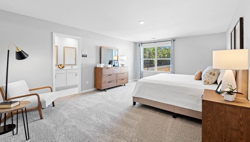 Primary bedroom with carpet and windows.