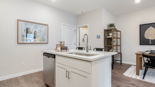 Scholls Meadow kitchen with stainless steel appliances, pantry, powder room, laminate flooring, quartz countertops, and in island sink