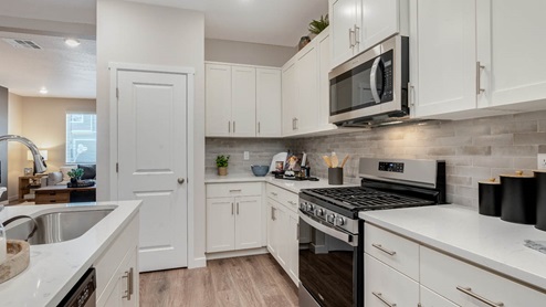 Scholls Meadow kitchen with stainless steel appliances, pantry, powder room, laminate flooring, quartz countertops, and in island sink
