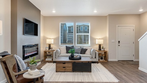 Scholls Meadow great room with windows, white walls, white couch with dark colored pillows, long coffee table, and end tables with lamps