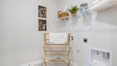 Scholls Meadow laundry room with hamper, white wire shelving, and white walls