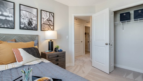 Scholls Meadow bedroom with bed frame and grey light blue bed sheets and pillows, carpet, and closet