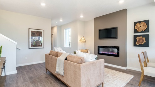 Scholls Meadow Great room with rug, electric fireplace, couch with throw blanket, laminate flooring, poster, lamp, window, and staircase