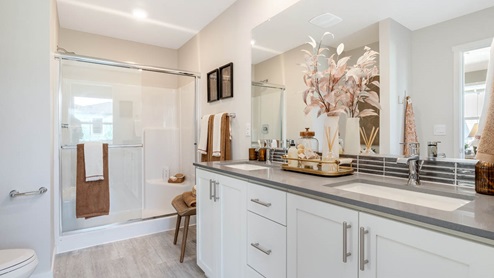 Scholls Meadow Primary Bathroom with quartz countertops, white shaker cabinets, lvt flooring, toilet, walk-in shower, towels, soap, mirror