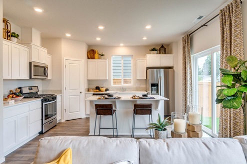 Marcola Meadows Kitchen with white quartz countertops, white shaker cabinets, stainless steel appliances, and an island with two chairs set at it