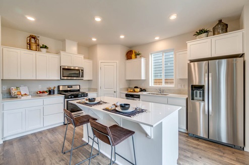 Marcola Meadows Kitchen with white quartz countertops, white shaker cabinets, stainless steel appliances, and an island with two chairs set at it