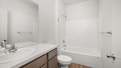 A bathroom with brown wood cabinets and white counters.