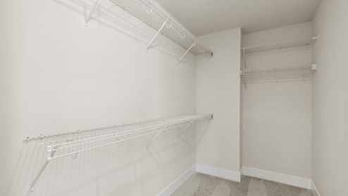 Wire shelving in walk-in closet of primary bedroom suite featured in Rainier floor plan
