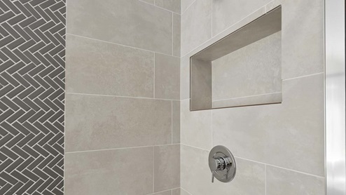 Close-up of built-in tiled cubby shelf inside shower of primary en suite bathroom