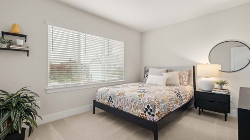 Secondary bedroom on upper floor with plush carpeting between third bedroom and primary bedroom