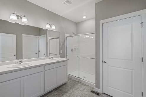 white cabinet bathroom with dual-basin sink and a shower