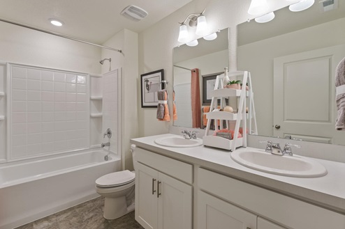 white cabinet bathroom with a dual-basin sink and a tub and toilet