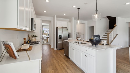 Gourmet kitchen viewing the front of the island, the stairs, and easy access to the dining room.