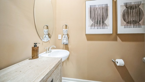 Powder bathroom with a pedestal sink, accent furniture with drawers for storage, and coordinating artwork.
