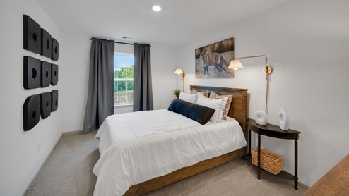 Secondary bedroom with a bed flanked by side tables and sconces in front of a window on the adjacent wall.