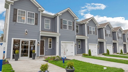Exterior front image of the model townhome with dark gray horizontal paneling, black shutters, and a white single car garage.