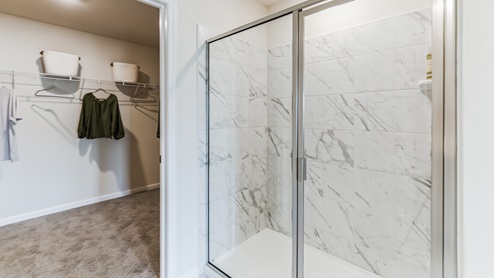 View of shower with glass doors and closet to the left.