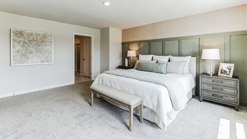 Large bedroom with king bed and entrance door in view.