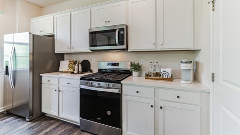 Wide view of the kitchen with island seating and stainless steel appliances.