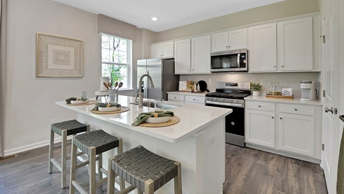 View of Kitchen with the back side of the island seating area. Stainless steel appliances with window to the left of the kitchen.